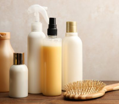 Hair care products on a wooden table on a neutral background.
